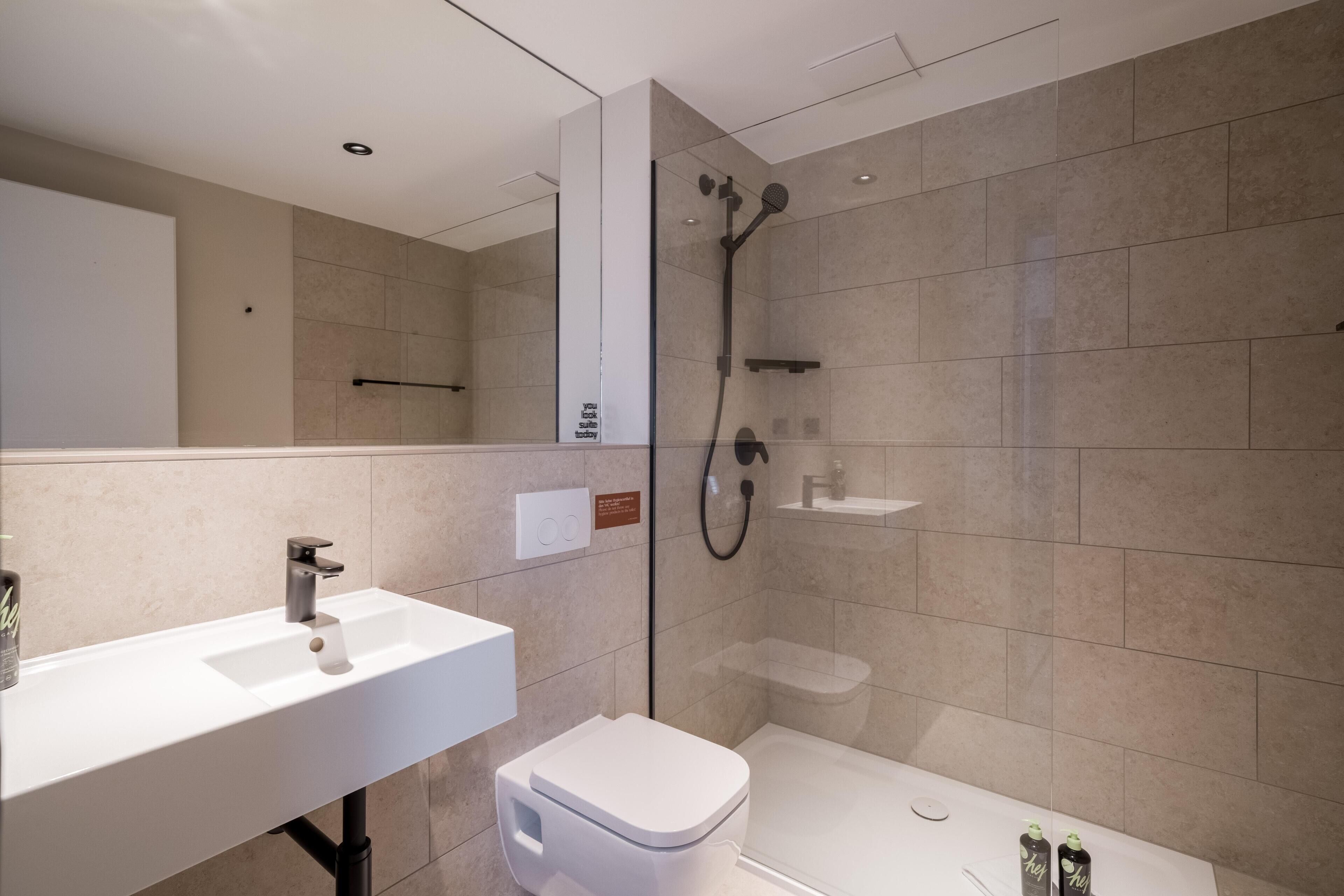 Un bagno moderno con lavandino, water e doccia bianchi.