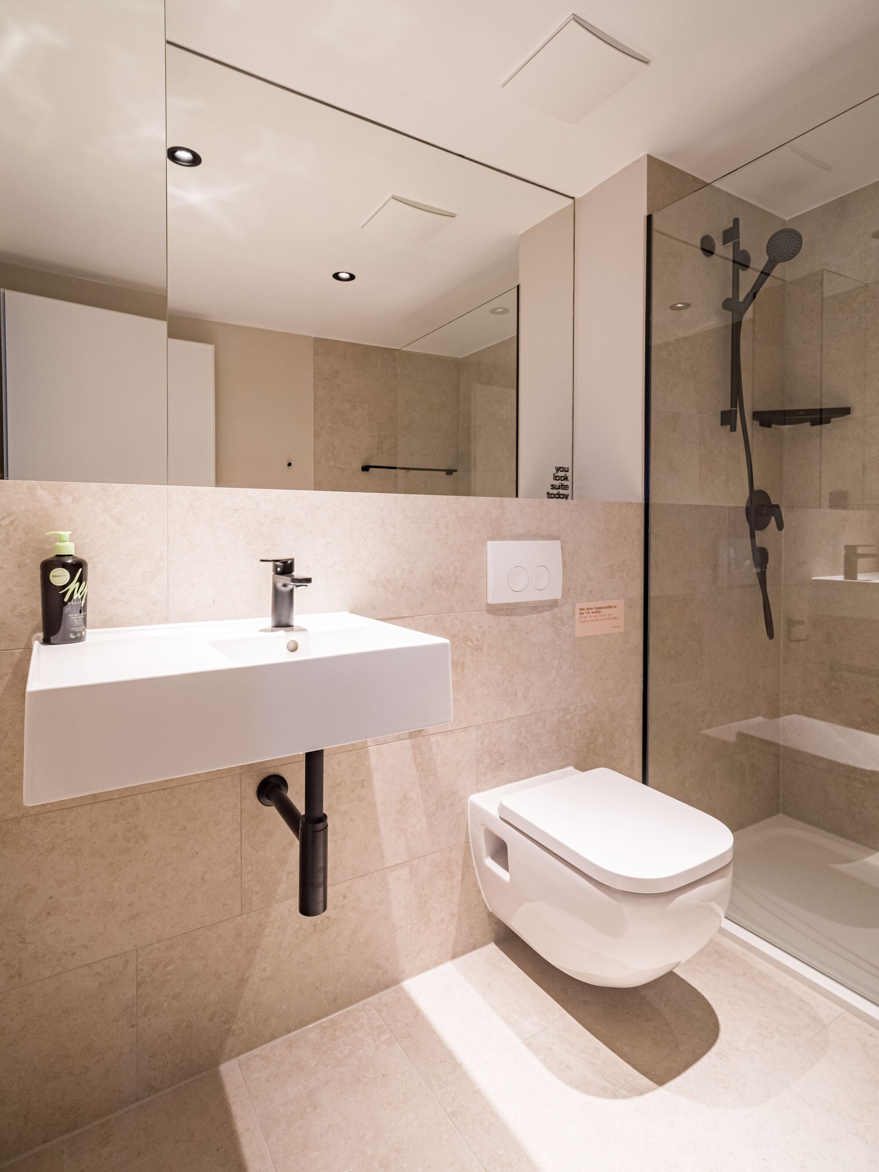 A modern bathroom with a white sink, toilet, and glass-enclosed shower.