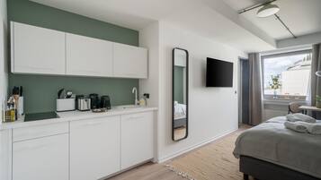 A modern bedroom with a bed, a bedside table, a mirror, and a window with curtains.