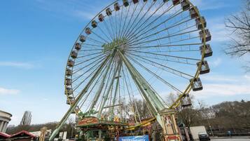 Une grande roue avec des cabines, un carrousel et une enseigne indiquant « Energie SaarLorLux ».