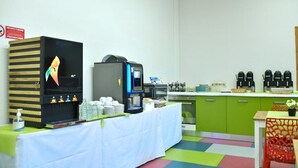 Een kamer met een koffiehoekje, een magnetron en een televisie.