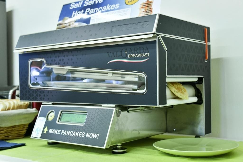 Ein Val Gorda Frühstücksgerät mit digitaler Anzeige und einem Schild darüber mit der Aufschrift 'Selbstbedienung Heiße Pfannkuchen'.