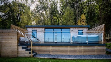 Enjoy a serene forest view from the large windows of this cabin, featuring a deck area with stairs.