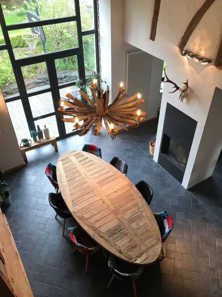 A dining area with a large oval table, chairs, a chandelier, and a fireplace.