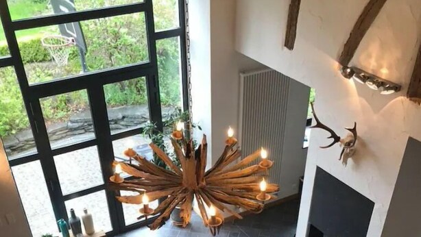 Ein Essbereich mit einem großen ovalen Tisch, Stühlen, einer Chandelier und einem Kamin.