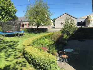 Un patio trasero con un trampolín, una piscina pequeña y un área de estar con una mesa y sillas.