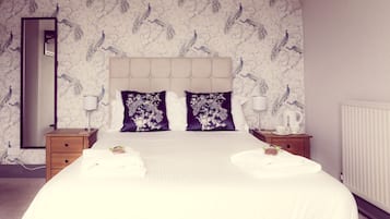 A hotel room with a large bed, two nightstands, a mirror, and a radiator.