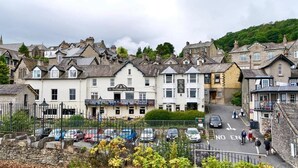 A town with historic buildings, a pub named 'The Concorde Inn', and a parking area with cars and pedestrians. - The Commodore Inn (Grange-over-Sands)