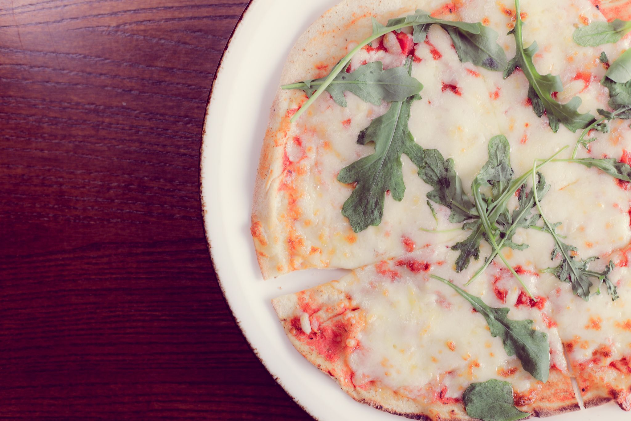A pizza on a white plate with a wooden table background.