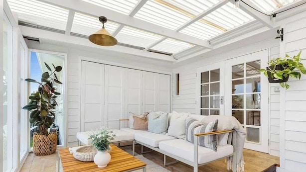 A sunlit room with a white sofa, a wooden table, and a hanging plant.