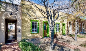A building with a yellow facade, green window frames, and a tree in front. - Downtown Rustic Adobe - Newly Renovated Historic Property - KING Bed & Parking (Tucson)