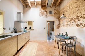 A kitchen with wooden cabinets, a sink, and a dining area with a table and chairs. - Downtown Rustic Adobe - Newly Renovated Historic Property - KING Bed & Parking (Tucson)