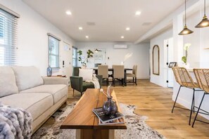 Una sala moderna con sofá, mesa de centro de madera y comedor con sillas.