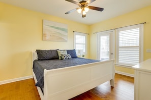 A bedroom with a bed, a ceiling fan, and two windows with blinds.