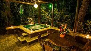 A hot tub area with a wooden deck, seating, and a table.