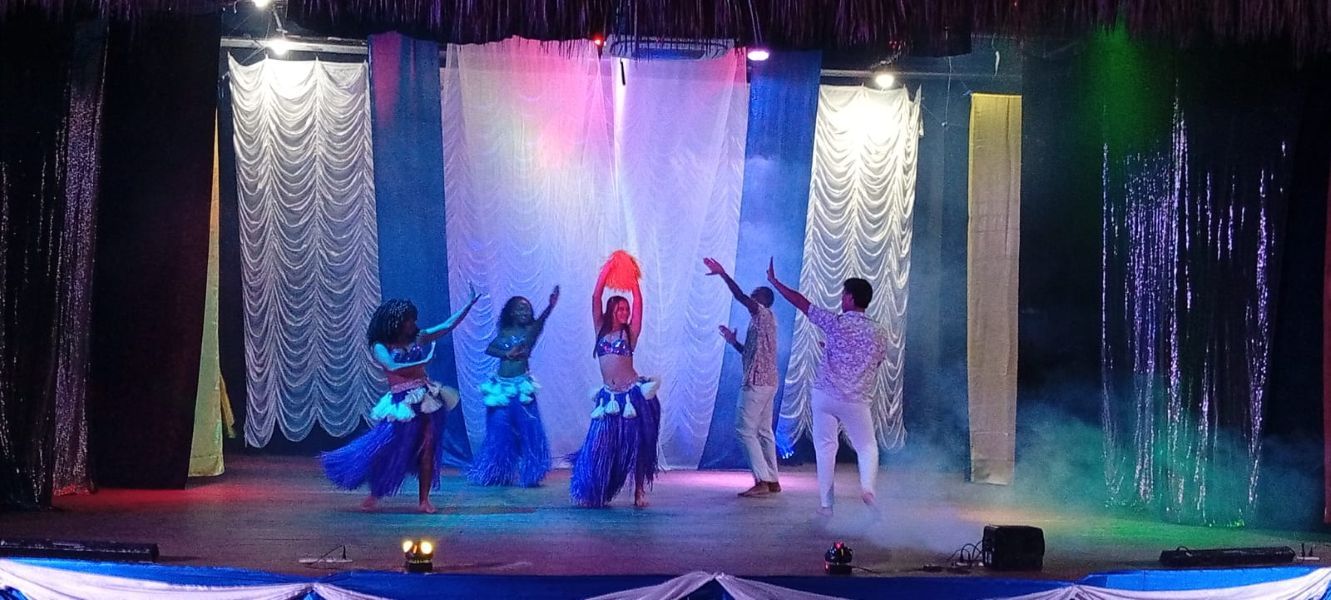 A stage with performers in costumes, a curtain backdrop, and stage lighting.