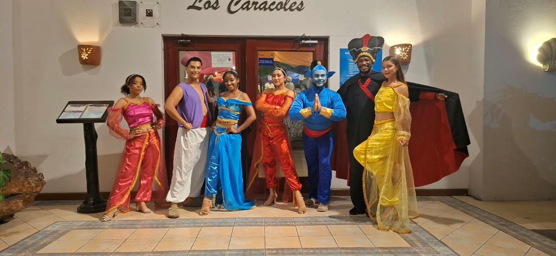 A group of people in costumes standing in front of a building with a sign that reads 'Los Caracoles'.