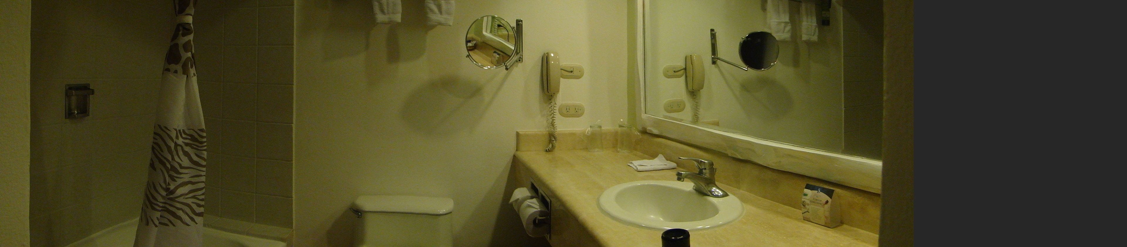 A bathroom with a toilet, sink, mirror, and shower curtain.