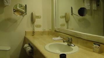 Un baño con inodoro, lavamanos, espejo y cortina de ducha.