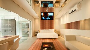 A modern hotel room with a bed, a sofa, a desk, and two TVs mounted on the wall. - Lush Motel Ipiranga (São Paulo)
