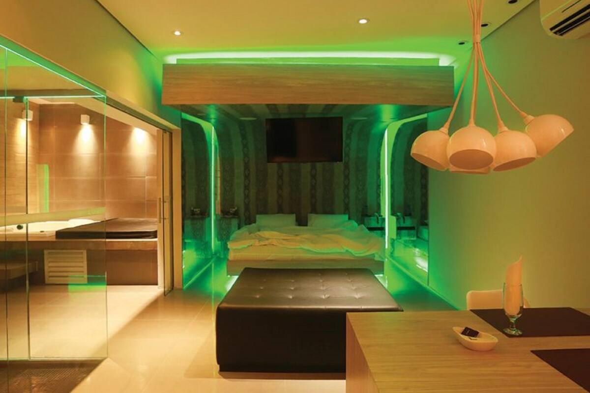 Un dormitorio moderno con cama, mesita de noche, espejo y lámpara colgante.