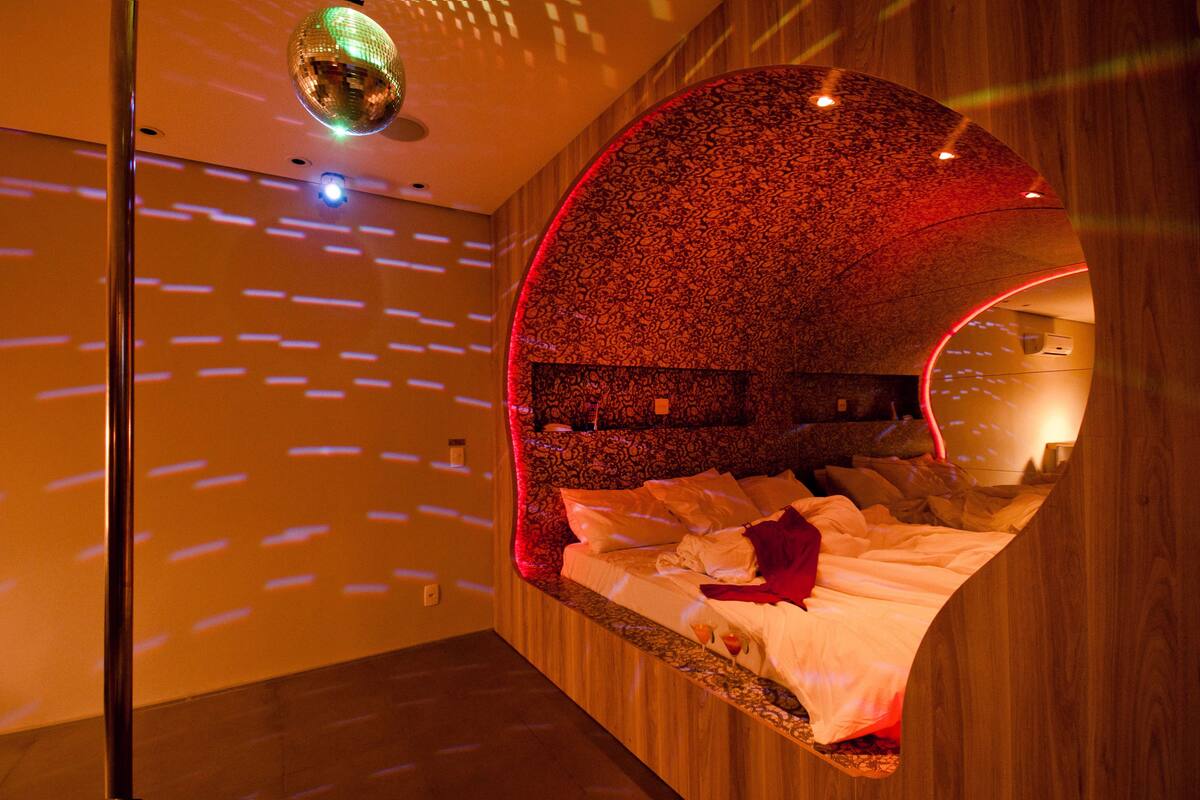 Una habitación con techo curvo, una bola de discoteca y una cama con una manta roja.