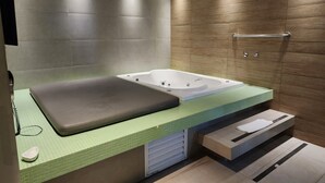 A modern bathroom with a bathtub, a bench, and a towel rack. - Lush Motel Ipiranga (São Paulo)
