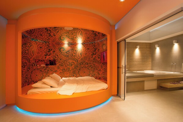 Une salle de bain moderne avec une baignoire aux lignes courbes, un espace douche et un grand miroir.