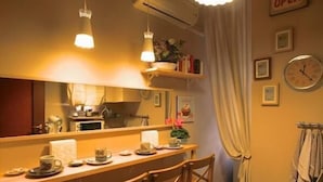 A cozy kitchen with wooden chairs, a dining table, pendant lights, and a clock on the wall. - Vatican Holiday (Rome)