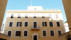 A building with a symmetrical facade, multiple windows with shutters, a central entrance with steps, and a small balcony above the entrance. - Vatican Holiday (Rome)
