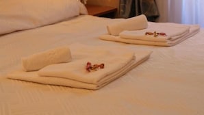 A hotel room with a neatly made bed, a bedside lamp, and a vase with flowers. - Vatican Holiday (Rome)