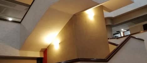 Un interior de varios niveles con un diseño de escalera moderno, que presenta una combinación de líneas rectas y curvas, e iluminación integrada en los peldaños.