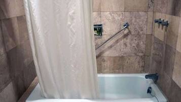 A bathroom with a bathtub, a shower curtain, and a towel rack.