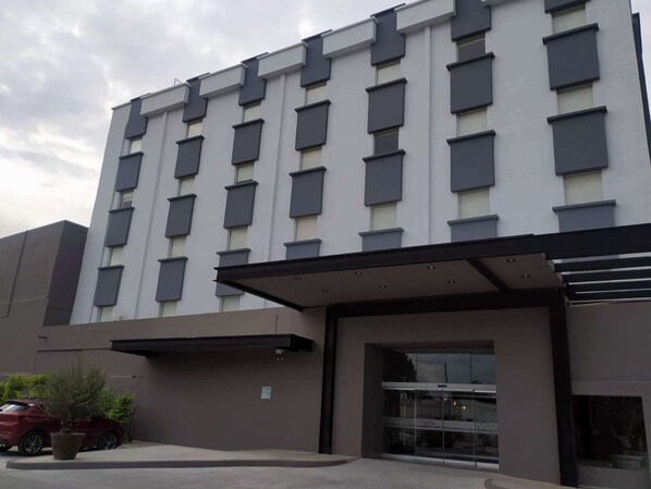 Een modern hotelgebouw met een platte gevel, grote ramen en een overdekte entree.
