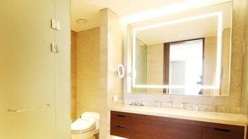 A modern bathroom with a large mirror, a toilet, and a vanity with drawers.