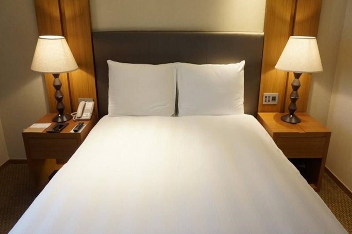 A hotel room with a large bed, two bedside tables with lamps, and a telephone on the left table.
