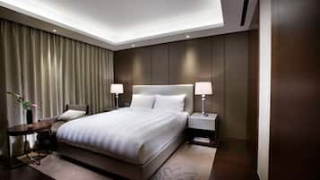 A modern hotel bedroom with a large bed, bedside lamps, a small table, and a decorative vase.