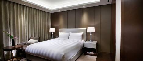 A modern hotel bedroom with a large bed, bedside lamps, a small table, and a decorative vase.