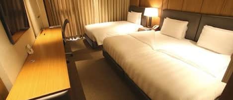 Una habitación de hotel con dos camas, un escritorio, una silla, una lámpara y una cortina.