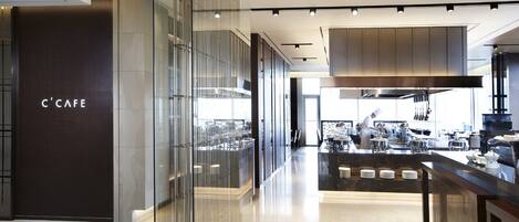 Un intérieur de café moderne au design épuré, comprenant une cloison en verre, un espace cuisine central et un comptoir.