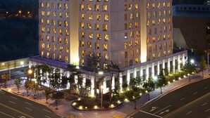 Un hotel de varios pisos con un patio central, ventanas iluminadas y una entrada destacada.
