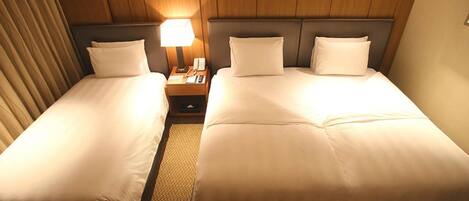 Ein Hotelzimmer mit zwei Einzelbetten, einem Nachttisch mit Lampe und einem Holz-Kopfteil.
