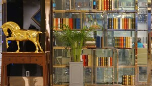 Een bibliotheekinterieur met boekenkasten, een gouden paardenbeeld en een potplant.