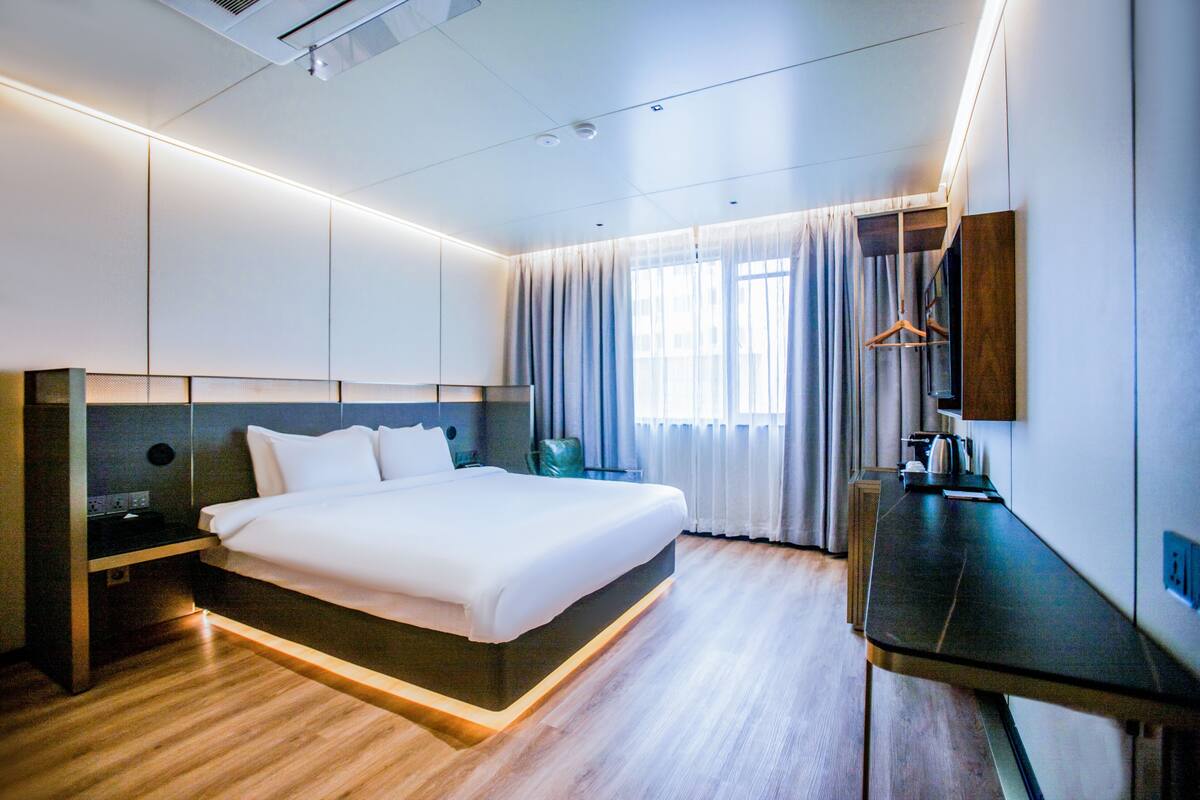 Une chambre d’hôtel moderne avec un grand lit, des tables de chevet, un bureau et un miroir.