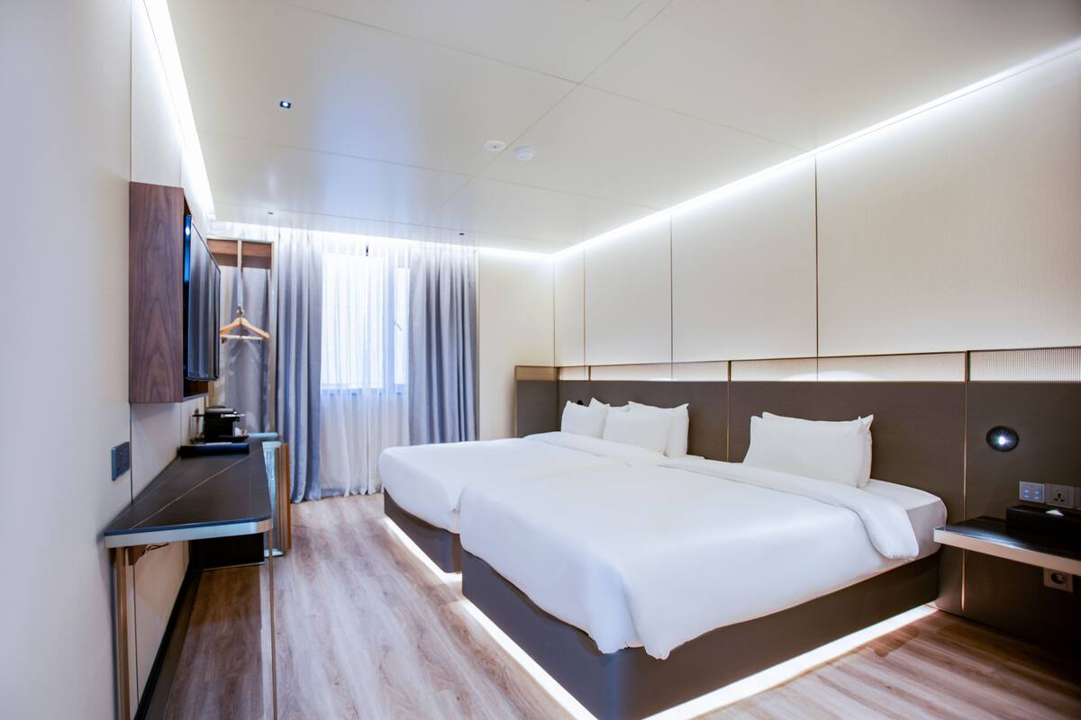 Ein modernes Hotelzimmer mit einem großen Bett, einem Schreibtisch und einem Kleiderschrank.