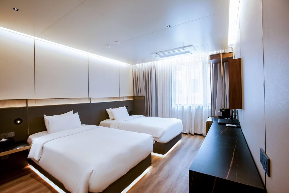Ein Hotelzimmer mit zwei Betten, einem Schreibtisch und einem großen Spiegel.