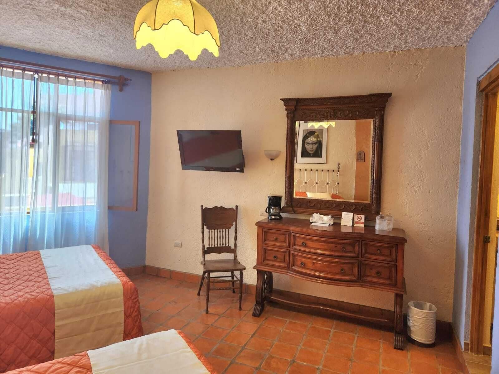 Une chambre d’hôtel avec deux lits, une télévision, une commode et une chaise.