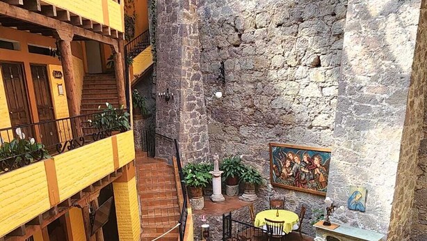 Un patio con mobiliario exterior, paredes de piedra y un mural.