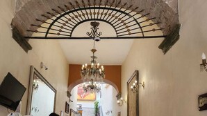 Una imponente escalera con un candelabro, una recepción y vistas del piso superior.