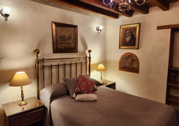 Un dormitorio con una cama, dos mesitas de noche con lámparas, un cabecero de madera y una obra de arte colgada en la pared.